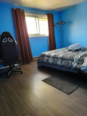 a bedroom with a bed and a chair and a window at Urban & Cozy in Guelph