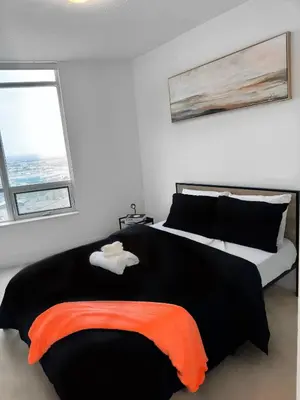 a bedroom with a large bed with an orange blanket at Modern One Bedroom Near Square One With Free Parking in Mississauga