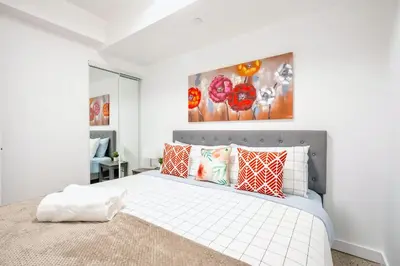 a bedroom with a large white bed with red pillows at Chic 2BR Basement Suite 2BR Toronto Getaway near Downtown - The Roland in Toronto
