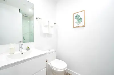 a white bathroom with a toilet and a sink at Peaceful 2BR Basement Suite Near Downtown Toronto - The Roland in Toronto