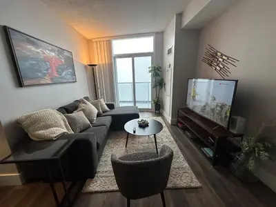 a living room with a couch and a flat screen tv at Stylish 2BR Suite by Square One in Mississauga