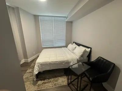a small bedroom with a bed and a chair at Stylish 2BR Suite by Square One in Mississauga