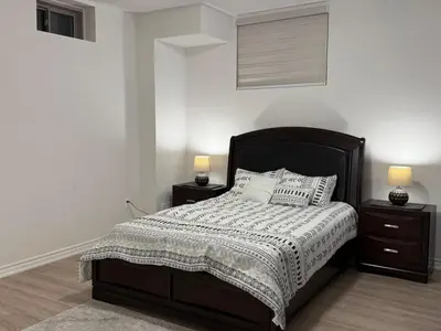 a bedroom with a bed with two night stands and two lamps at Modern Luxury Basement Suite in Oakville