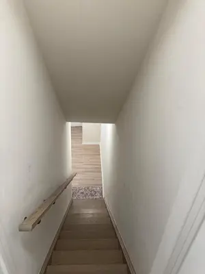 a staircase with white walls and a wooden railing at Modern Luxury Basement Suite in Oakville