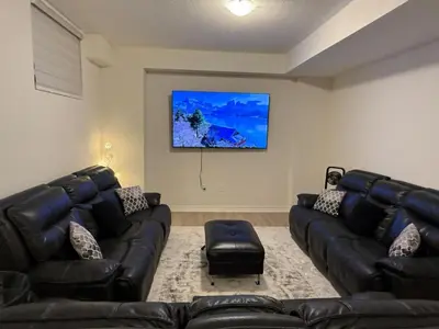 a living room with two leather couches and a flat screen tv at Modern Luxury Basement Suite in Oakville