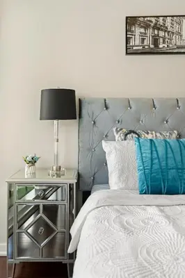 a bed with a silver headboard and a table with a lamp at Luxury Lakeview Downtown Condo, CN Tower, Rogers Center, Scotia Arena, Lake View with Free Parking in Toronto
