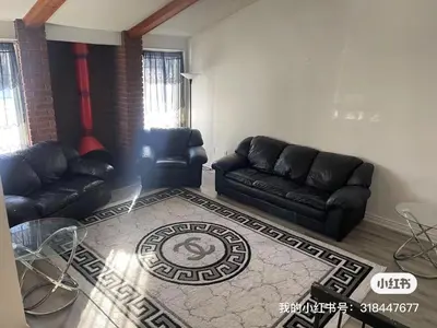 a living room with black leather couches and a rug at scarborough home in Toronto