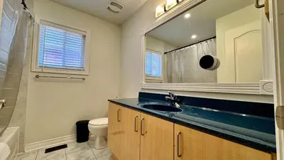 a bathroom with a sink and a toilet and a mirror at Spacious 4BD Oasis with Sauna in Mississauga