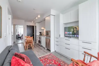 a living room with a couch and a tv and a kitchen at Downtown 1BR City Stay with Balcony and Fast Wi-Fi in Toronto