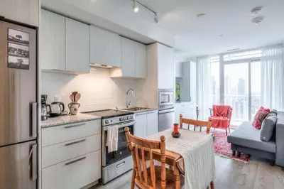 a kitchen with white cabinets and a table with a dining room at Downtown 1BR City Stay with Balcony and Fast Wi-Fi in Toronto