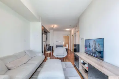 a living room with a white couch and a tv at 1BR plus Den Condo with Balcony in Heart of Toronto in Toronto
