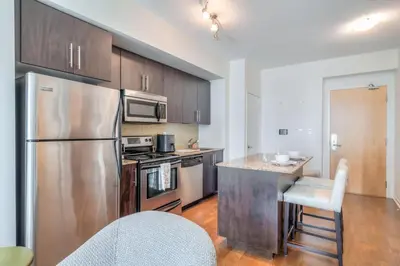 a kitchen with stainless steel appliances and wooden cabinets at 1BR plus Den Condo with Balcony in Heart of Toronto in Toronto