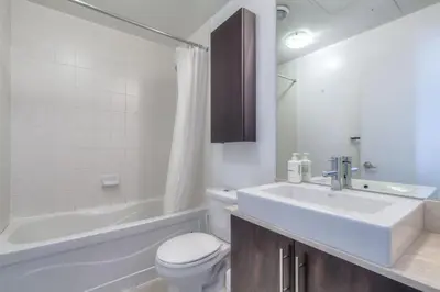 a bathroom with a sink and a toilet and a tub at 1BR plus Den Condo with Balcony in Heart of Toronto in Toronto