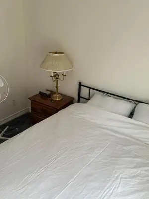 a white bed with a lamp on a night stand at Goldwin's Place in Toronto