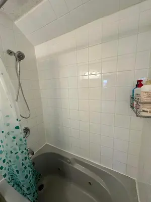 a bathroom with a tub and a white tiled wall at Goldwin's Place in Toronto