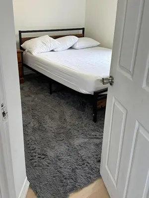 a bedroom with a bed with white sheets and pillows at Goldwin's Place in Toronto