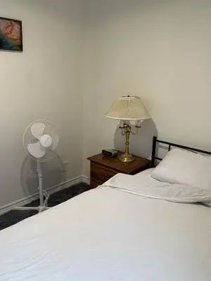 a bedroom with a bed and a lamp and a fan at Goldwin's Place in Toronto