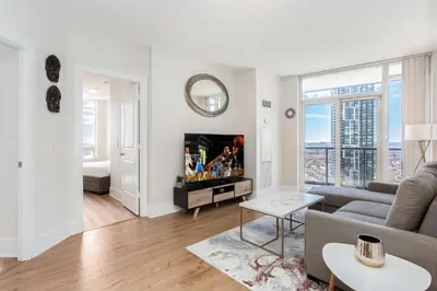 a living room with a couch and a tv at Lavish 2BR 2Bath Condo Steps to Square One Mall in Mississauga