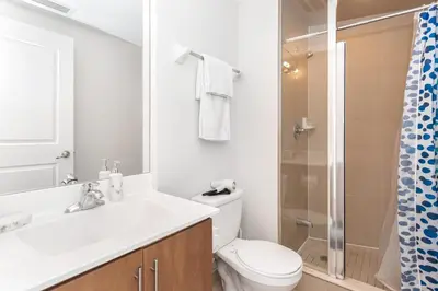 a white bathroom with a toilet and a shower at Lavish 2BR 2Bath Condo Steps to Square One Mall in Mississauga