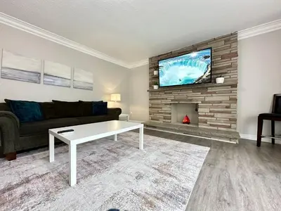 a living room with a couch and a tv above a fireplace at Mountain View House - Sleeps 14 in St. Catharines