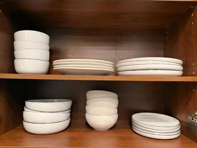 a shelf filled with white plates and bowls at Large Downtown 2Br condo with Parking steps to Eaton Centre, UofT and SickKids in Toronto