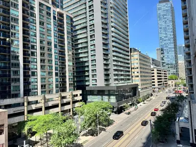 a city with tall buildings and a street with cars at Large Downtown 2Br condo with Parking steps to Eaton Centre, UofT and SickKids in Toronto