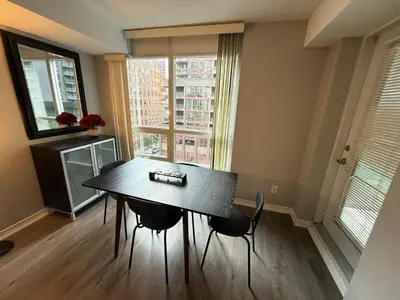 a dining room with a table and chairs and a window at Large Downtown 2Br condo with Parking steps to Eaton Centre, UofT and SickKids in Toronto