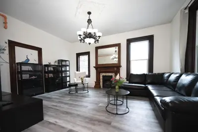 a living room with a black leather couch and a fireplace at Comic House with Climbing Wall & Themes in Chesley