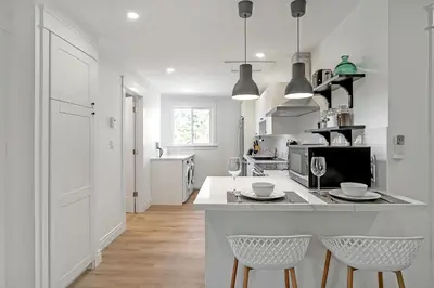 a white kitchen with two chairs and a counter at The Dove Loft Near DT & Hospital in Peterborough