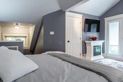 a bedroom with a bed and a tv on the wall at Glyn Rhosyn Balcony Riverview in Stratford