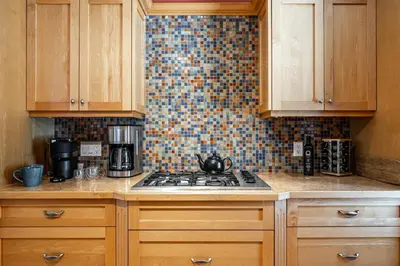 a kitchen with a stove and a tiled wall at Glyn Rhosyn Balcony Riverview in Stratford
