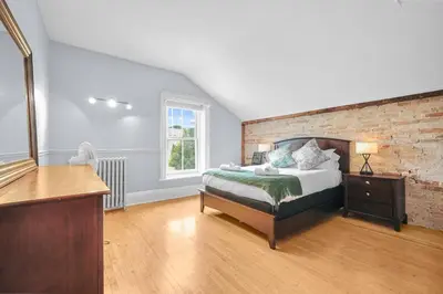 a bedroom with a bed and a brick wall at Mins to Beach Downtown 5BR w Pool Patio and BBQ in Cobourg