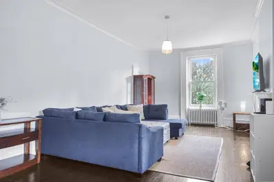 a living room with a blue couch and a window at Mins to Beach Downtown 5BR w Pool Patio and BBQ in Cobourg