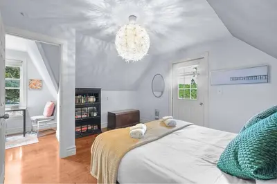 a bedroom with a white bed and a chandelier at 2BR Downtown Retreat Mins to Beach BBQ and Firepit in Cobourg