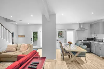 a living room and kitchen with a red couch and a table at 2BR Downtown Retreat Mins to Beach BBQ and Firepit in Cobourg