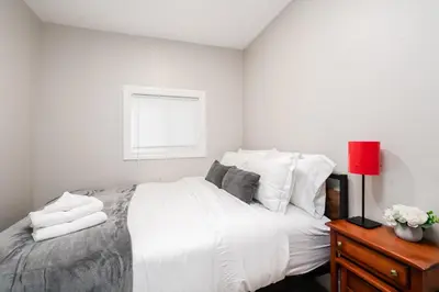 a bedroom with a large white bed with a red lamp at Waterfront Bliss Firepit and BBQ in Hanover