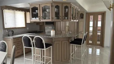 a kitchen with wooden cabinets and bar stools at Spacious, Peaceful & Perfectly Located - 4BR,3BA in London