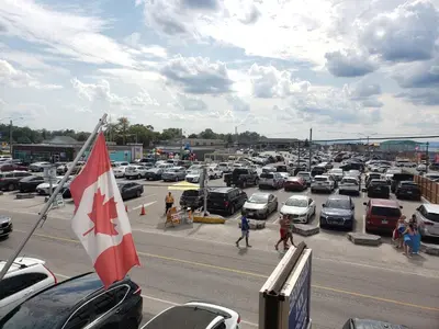 a parking lot with a canadian flag and cars parked at Georgian Inn Motel in Wasaga Beach