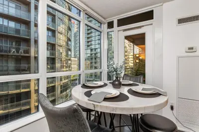 a table and chairs in a room with large windows at Downtown Urban Oasis I Entertainment District in Toronto