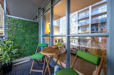 a balcony with a wooden table and green chairs at Downtown Urban Oasis I Entertainment District in Toronto