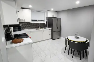 a white kitchen with a table and a refrigerator at Gracy's property in Thamesford