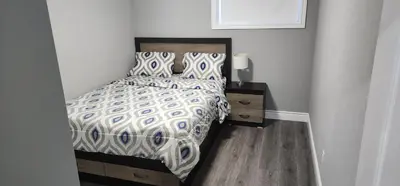 a bedroom with a bed and a table with a lamp at Gracy's property in Thamesford