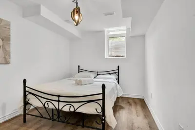 a bedroom with a bed in a room with white walls at 5mins Shopping, Stylish Modern 2BR Kitchen Suite in Markham in Markham