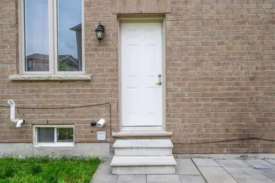 a white door on the side of a brick building at 5mins Shopping, Stylish Modern 2BR Kitchen Suite in Markham in Markham