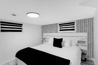 a black and white bedroom with a white bed at Sleep 8 Hot Tub Backyard Retreat 5 Min To Falls in Niagara Falls