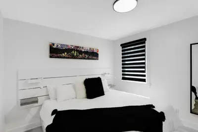 a white bedroom with a white bed and a window at Sleep 8 Hot Tub Backyard Retreat 5 Min To Falls in Niagara Falls
