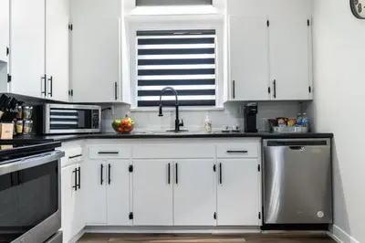 a kitchen with white cabinets and a sink at Outdoor Sauna Hot Tub Playroom Port Dallhousie in St. Catharines