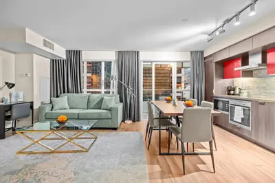 a living room with a green couch and a table at Classy 1-Bedroom & Den Condo in Heart of Downtown in Toronto