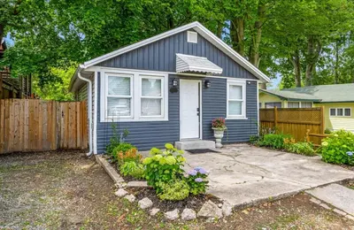 a small blue house with a fence and some flowers at Crystal Tides Retreat in Fort Erie