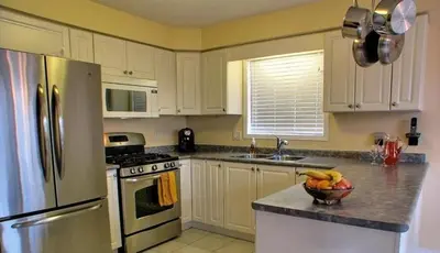 a kitchen with white cabinets and a bowl of fruit on the counter at HB Guest Home in Waterloo
